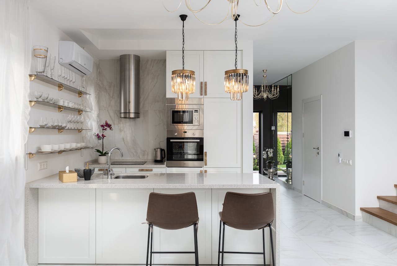 story-02 Interior of contemporary kitchen with modern appliances and chairs at white counter near wall with shelves in spacious apartment near stairs